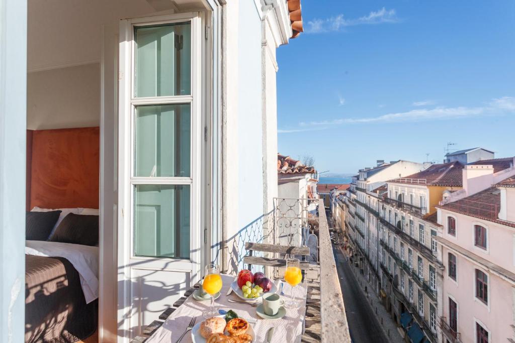 a balcony with a table with food and fruit on it at Madalena EXCLUSIVE SUITES in Lisbon