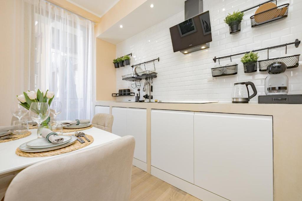a kitchen with white cabinets and a table with chairs at Appartamento Visconti by Rhospitality it in Rho
