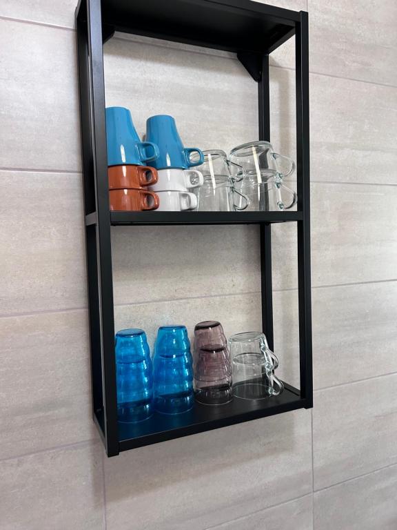 a black shelf with glasses and cups on it at EM House in Otopeni