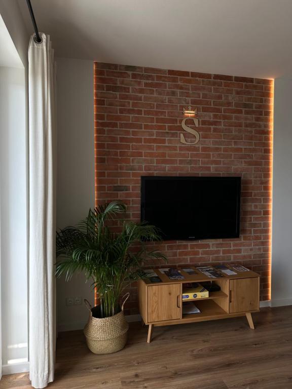 サンドミエシュにあるApartament na Wzgórzuのレンガの壁にテレビ付きのリビングルーム