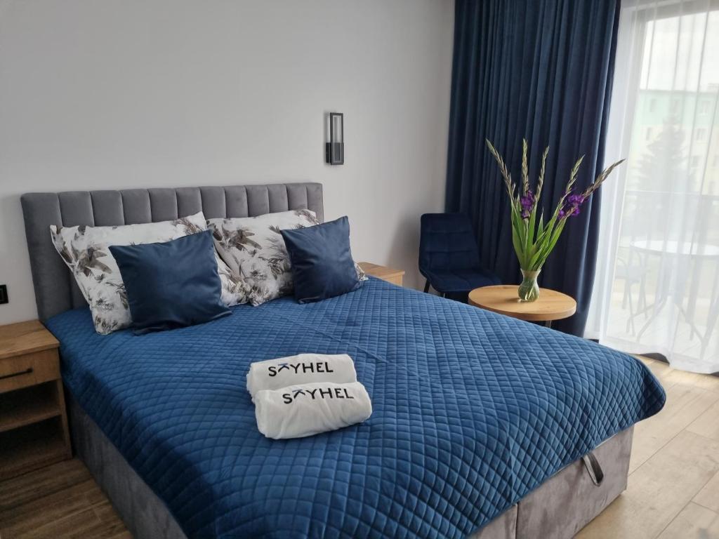 Una cama con un edredón azul con un pequeño cartel. en SkyHel Apartament 202, en Hel