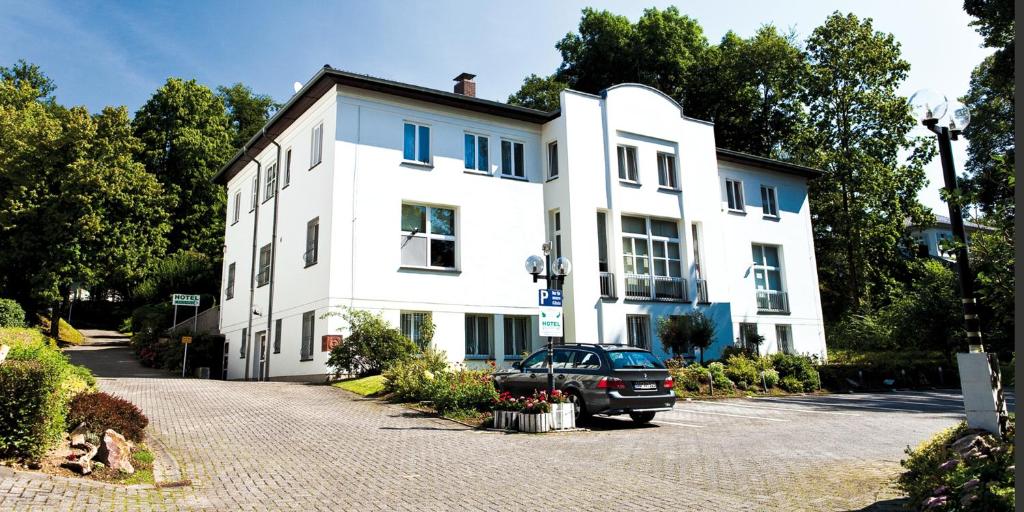 ein weißes Gebäude mit einem davor geparkt in der Unterkunft Hotel Haus am Park in Bad Homburg vor der Höhe