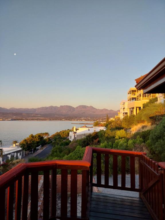 a wooden balcony with a view of the water at Bay View Cabin in Gordonʼs Bay