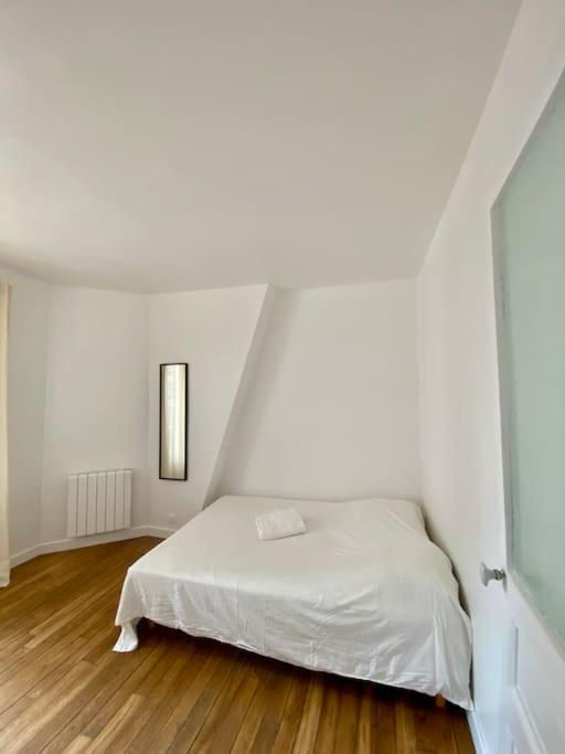 - un lit blanc dans une chambre blanche dotée de parquet dans l'établissement Appartement - Proche Paris - Stade de France, à Saint-Denis