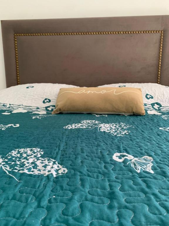 a bed with a blue and white comforter and a pillow at Angelina in Posadas