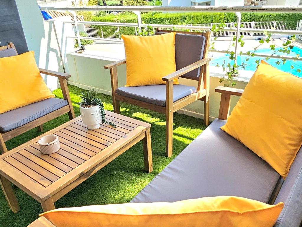 une terrasse avec deux chaises, une table en bois et une table dans l'établissement Appartement bord de mer, piscine, à Villeneuve-Loubet