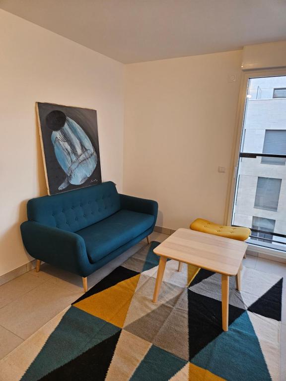 Una sala de estar con un sofá azul y una mesa. en TERRASSE La Varenne, en Saint-Maur-des-Fossés