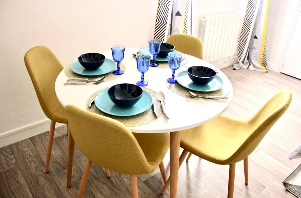 une table blanche avec des chaises, des assiettes et des verres dans l'établissement appartement 2 pieces tendance, à Bobigny