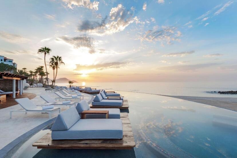 a row of white lounge chairs on a swimming pool at Beach&Golf suites in El Bedito