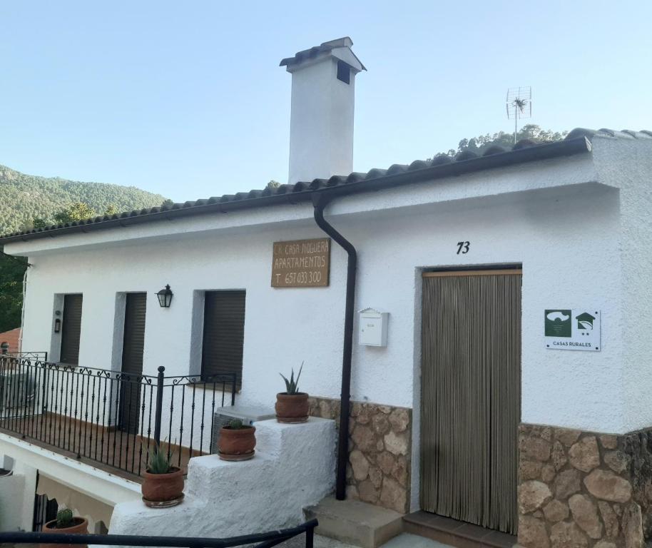ein weißes Gebäude mit einer Tür und Topfpflanzen in der Unterkunft Casas rurales Casa Noguera 2 in La Casa de la Noguera
