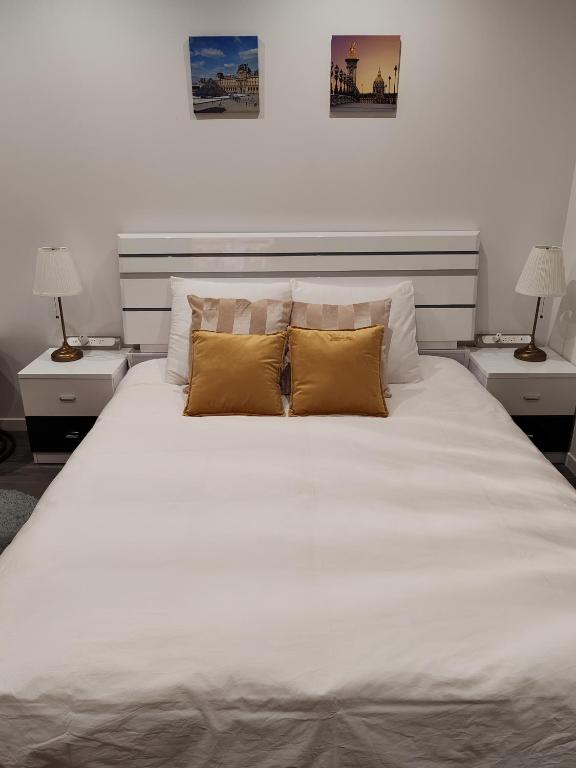 une chambre avec un grand lit blanc avec deux lampes dans l'établissement appartement champs elysees, à Paris