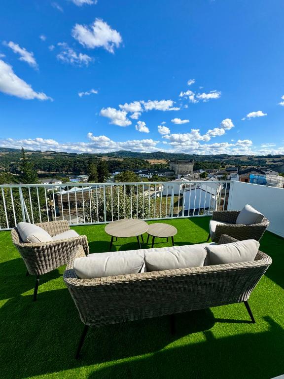 a patio with a couch and chairs on a balcony at PortoHome Ático in Portomarin