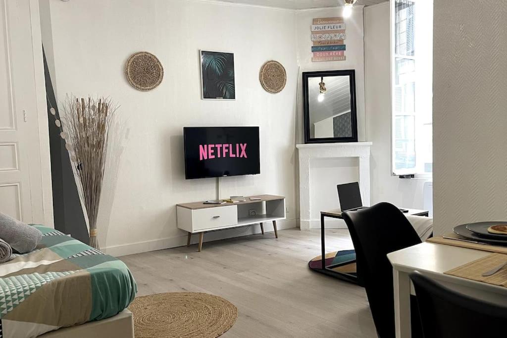 un salon avec une télévision sur un mur dans l'établissement La Petite Fleur - Centre ville, à Niort