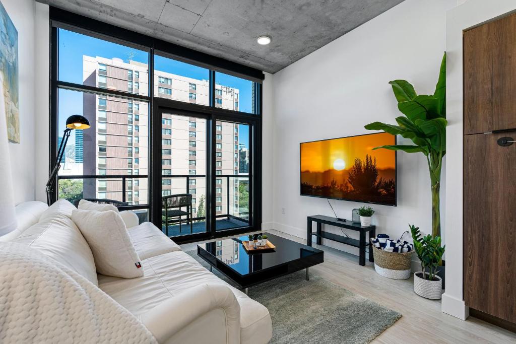 a living room with a white couch and large windows at City Views! Luxury King bed gym pool HTub in American Towers Condominium
