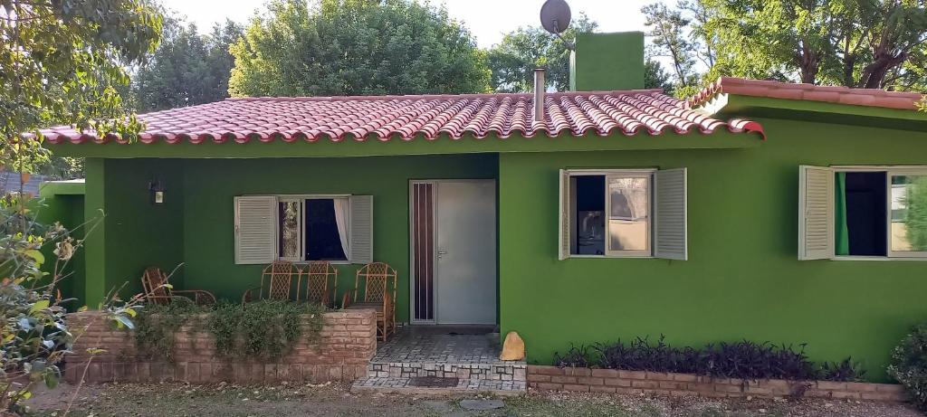 a green house with a white door and chairs at Casa Icho Cruz in Villa Icho Cruz
