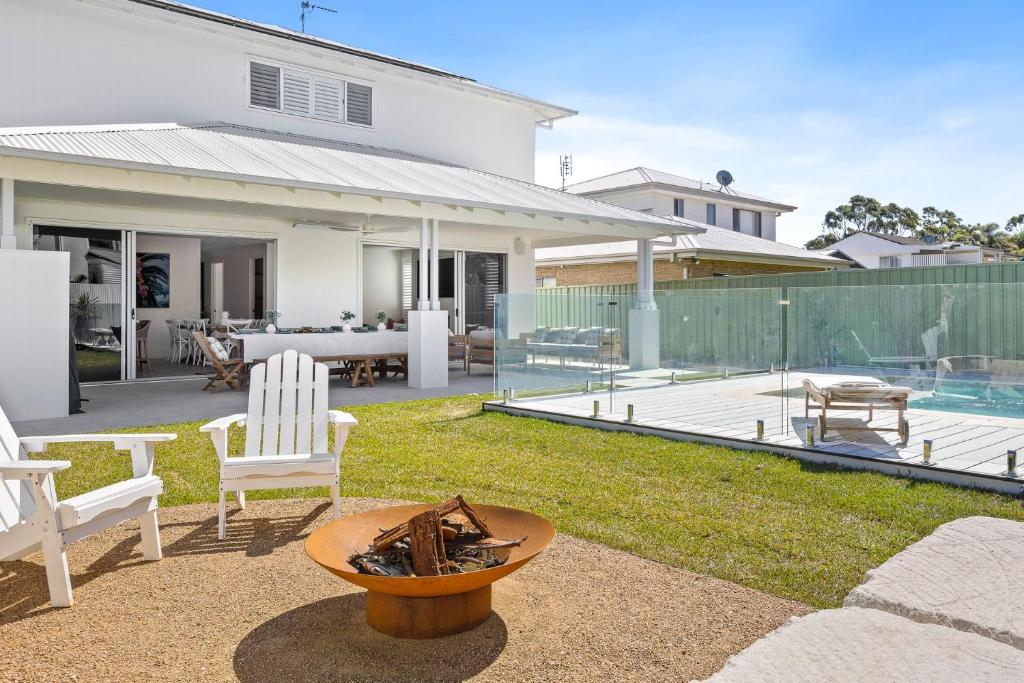 einen Hinterhof mit Stühlen, einem Tisch und einem Haus in der Unterkunft Welcome to Sandy Bottoms! in Shoalhaven Heads