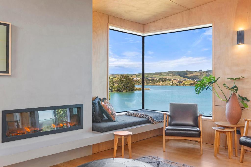 a living room with a fireplace and a view of the water at On Point House, Luxury design, Water Views in Raglan