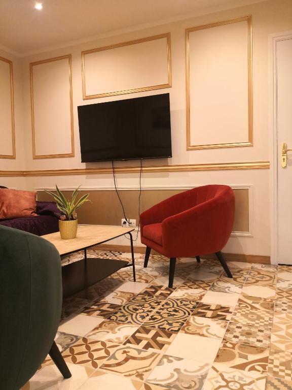 un salon avec une télévision et un fauteuil rouge dans l'établissement Résidence Hélène Boucher - Idéal entre Aéroport Paris Orly et Paris Centre 20mn, à Villeneuve-Saint-Georges