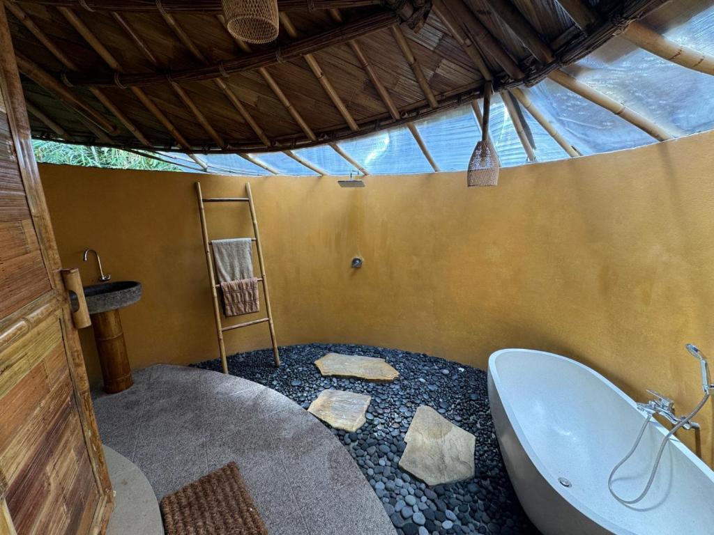 un bagno con vasca e lavandino di Bamboohouse pondok salacca #salacca inn a Manggis
