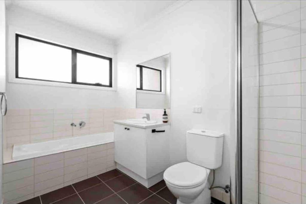 a bathroom with a toilet and a sink and a tub at Melbourne home close to Airport & Train Station in Melbourne