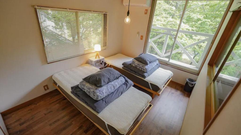 two beds in a room with a window at clover house in Nasu