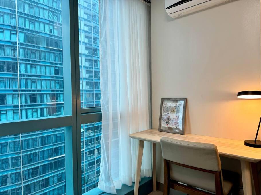 a desk with a chair in front of a window at BGC 1BR unit linked to Uptown Mall with own parking in Manila