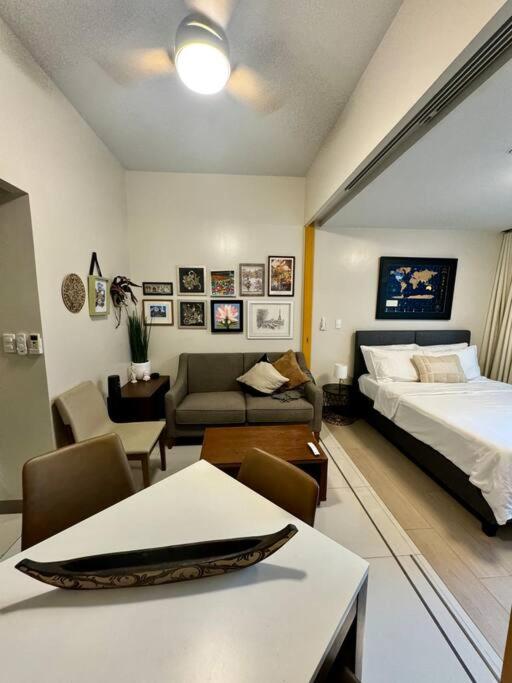a bedroom with a bed and a living room at BGC 1BR unit linked to Uptown Mall with own parking in Manila