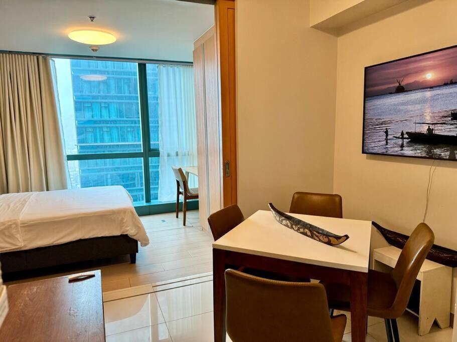 a hotel room with a bed and a table and chairs at BGC 1BR unit linked to Uptown Mall with own parking in Manila