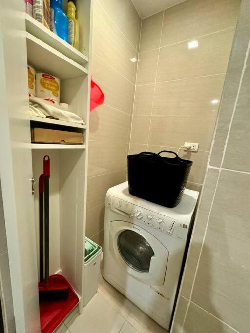 a small kitchen with a washing machine in a closet at BGC 1BR unit linked to Uptown Mall with own parking in Manila