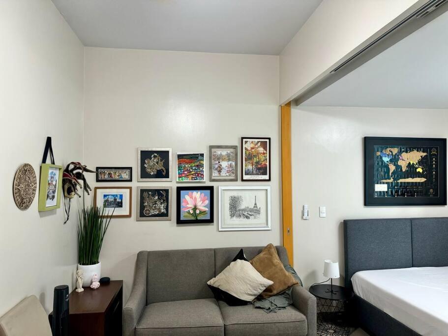 a bedroom with a couch and pictures on the wall at BGC 1BR unit linked to Uptown Mall with own parking in Manila