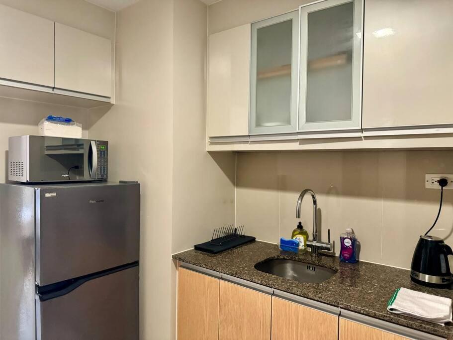 a kitchen with a sink and a refrigerator at BGC 1BR unit linked to Uptown Mall with own parking in Manila