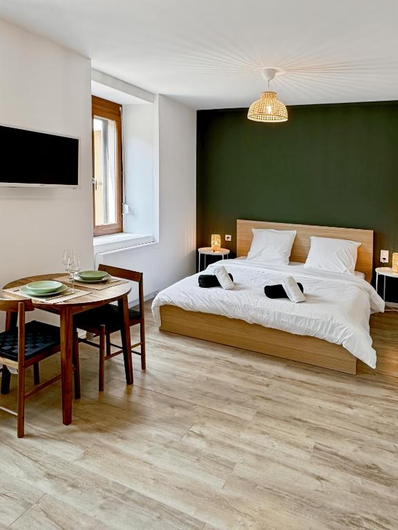 Un dormitorio con una cama grande y una mesa. en Une touche de vert, en Mulhouse