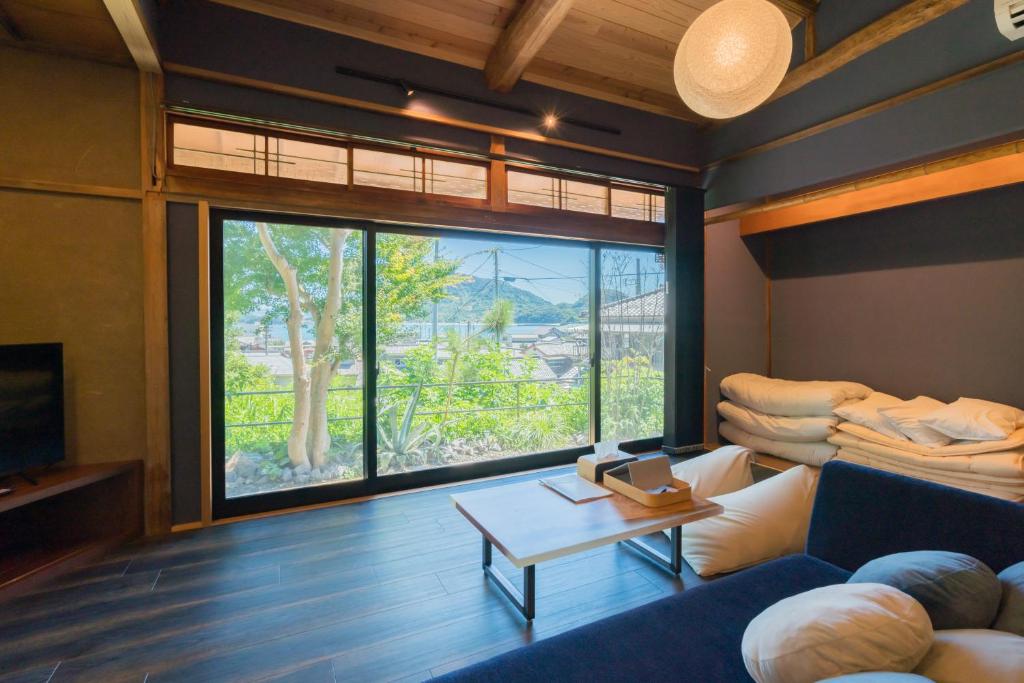 un soggiorno con divano blu e una grande finestra di 由良民泊島宿 a Matsuyama