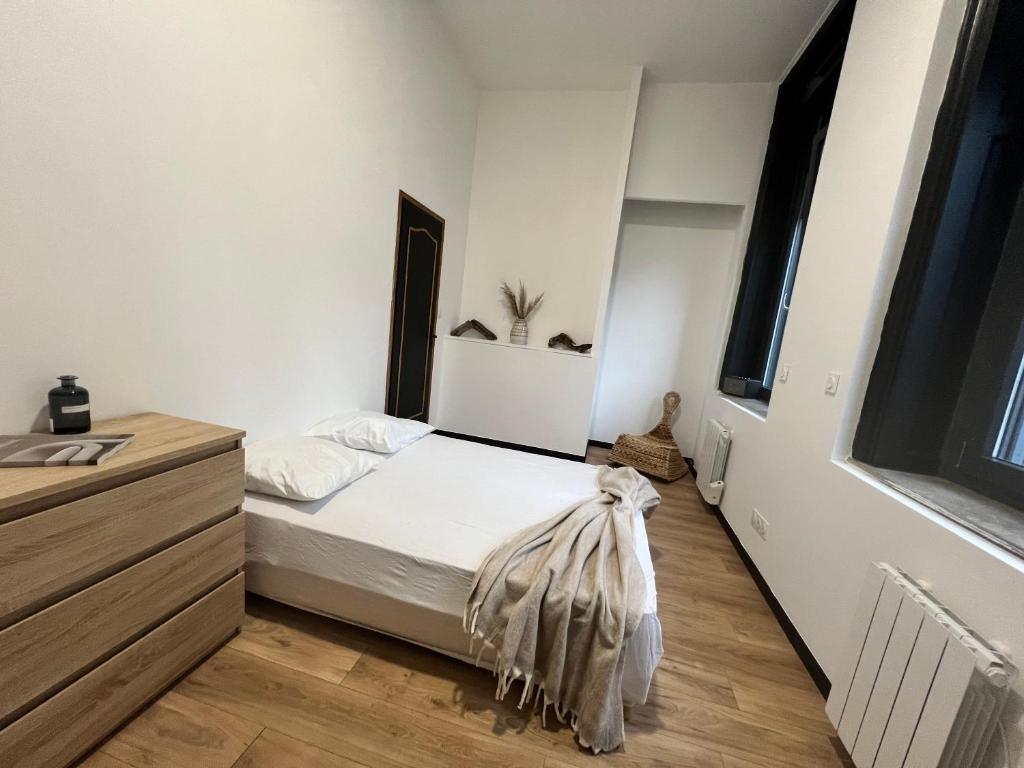 une chambre avec un lit blanc et un parquet dans l'établissement Appartement cosy Centre-ville, à Roubaix
