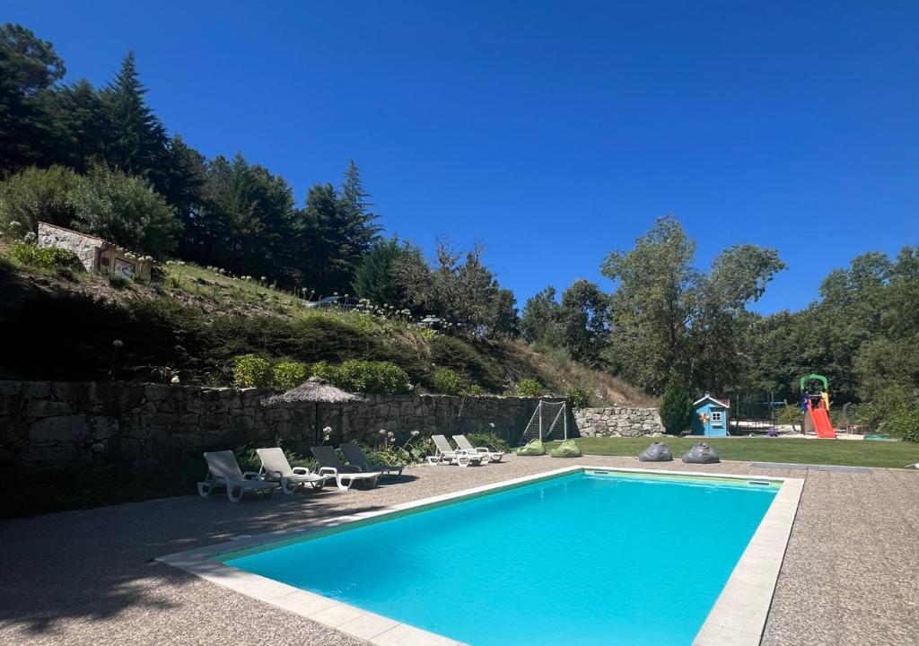 a swimming pool with two lounge chairs and a playground at Casa Moinho da Mouta in Parada de Pinhão