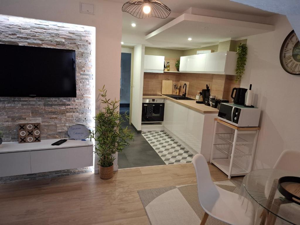 a living room with a kitchen with a tv on a brick wall at Bel Appartement, Sélestat in Sélestat