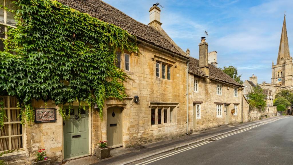 an old stone building on a street with a church at Spinner's Cottage in Burford