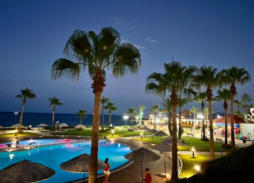a pool with palm trees and the ocean at night at Marina Beach-Mdiq- Seaside Luxury Resort in Restinga Smir