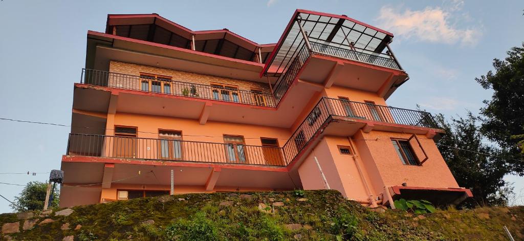 an orange building with balconies on top of a hill at Sejal Homestay in Shimla