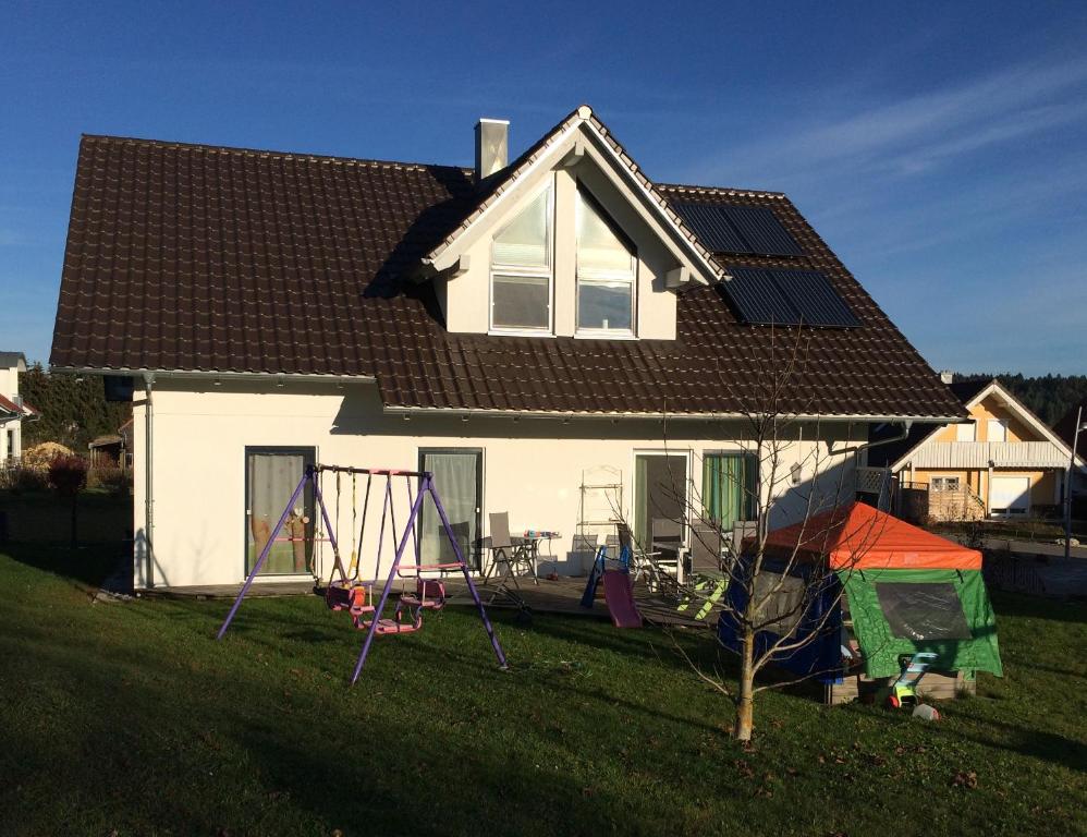 ein weißes Haus mit Dachschräge und Spielplatz in der Unterkunft Ferienwohnung Ahorn in Hohenstein