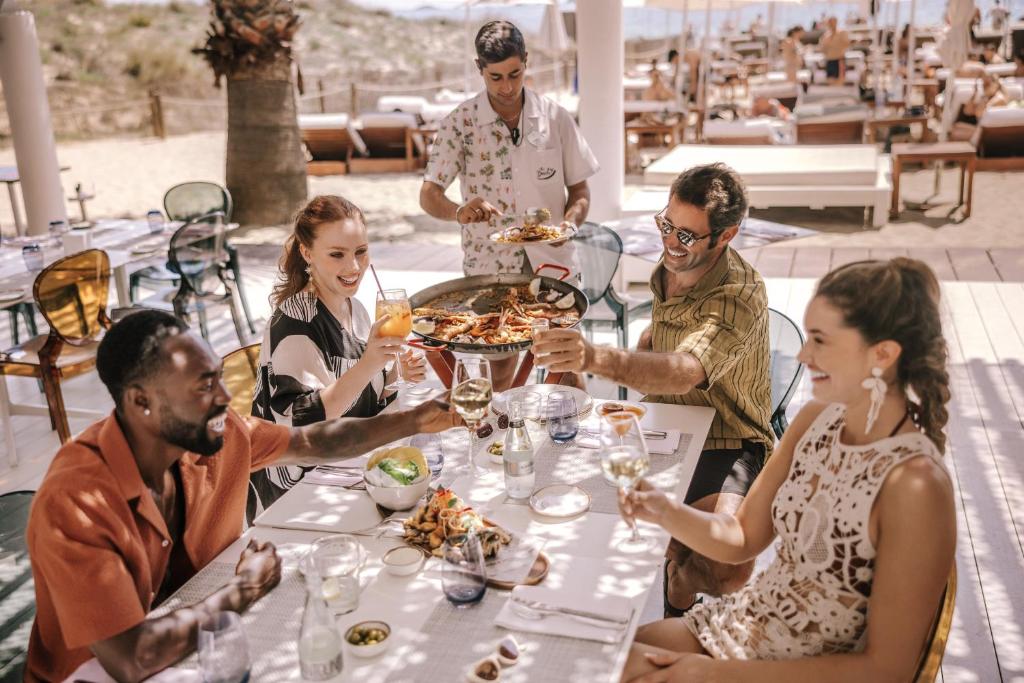 a group of people sitting around a table eating food at Hard Rock Hotel Ibiza in Playa d'en Bossa