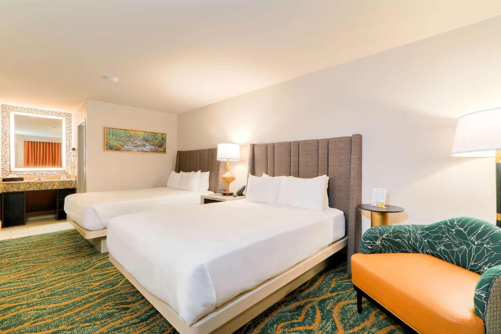 a hotel room with two beds and a chair at Quality Inn Near the Island Pigeon Forge in Pigeon Forge