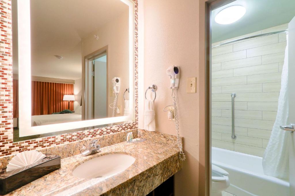 a bathroom with a sink and a mirror and a tub at Quality Inn Near the Island Pigeon Forge in Pigeon Forge