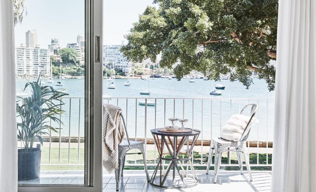 a balcony with a table and chairs and a view of the water at Exclusive Darling Apt Harbour View Balcony in Sydney