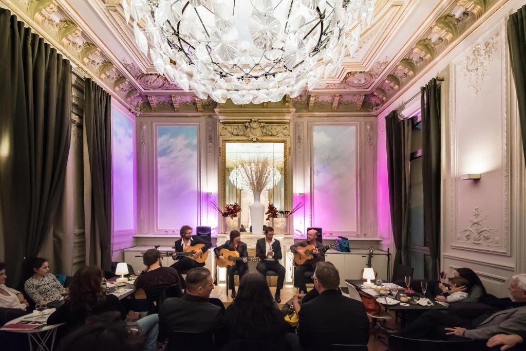 a group of people sitting at tables in a room with a chandelier at Hotel C2 in Marseille