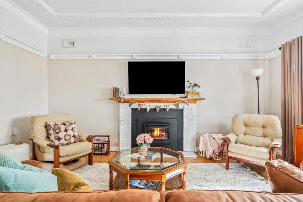 Una sala de estar con chimenea y televisión. en Deodar Cottage Amid Century Old Trees, en Wentworth Falls