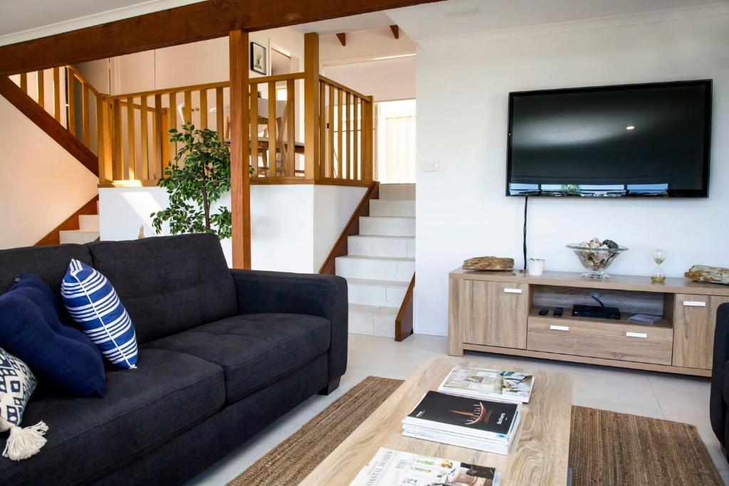 a living room with a couch and a flat screen tv at Blissful Stay Moments From the Beach in Surf Beach