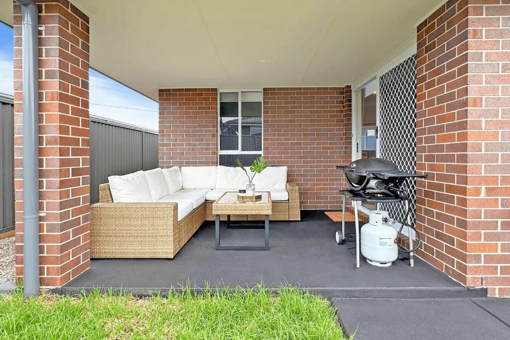 a patio with a white couch and a grill at Vineyard Oasis Heart of the Hunter in Cessnock