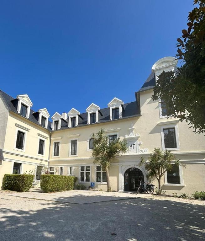 a large white building with palm trees in front of it at Hotel de France in Saint-Pol-de-Léon
