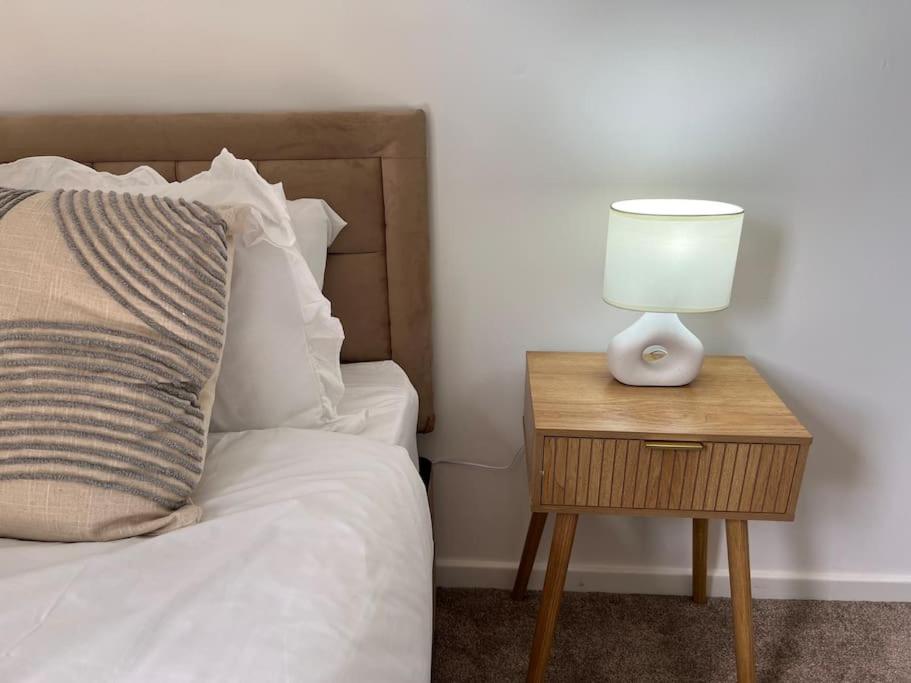 a bed with a nightstand with a lamp on it at Charming, Modern Flat sleeps 5 in Tayport